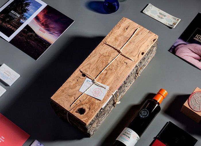 botella de diseño de vidrio oscuro con etiqueta, serigrafía a un color y capuchón acompañada de una caja de madera muy rústica